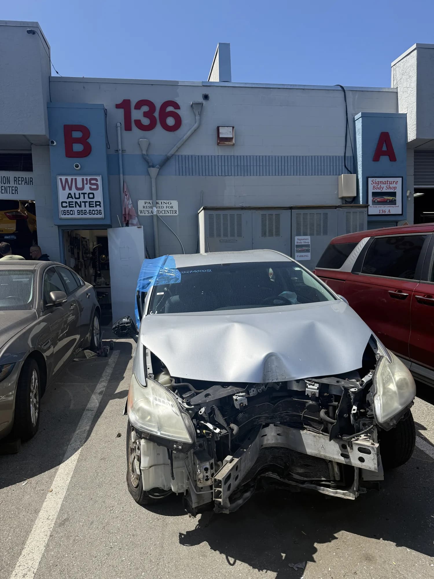 Car with severe front-end collision damage parked outside the repair bays