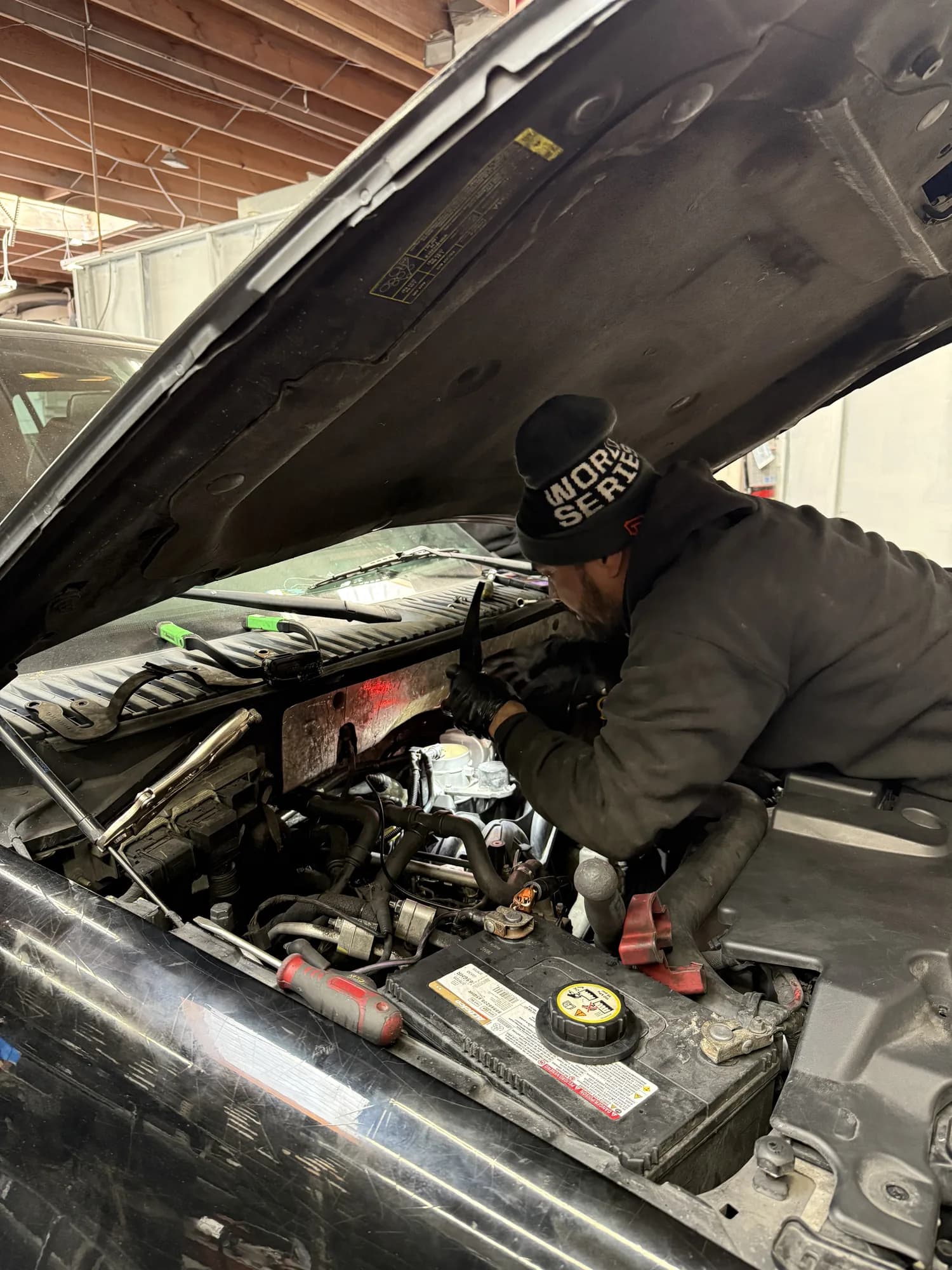 Technician working in an engine bay with the hood raised